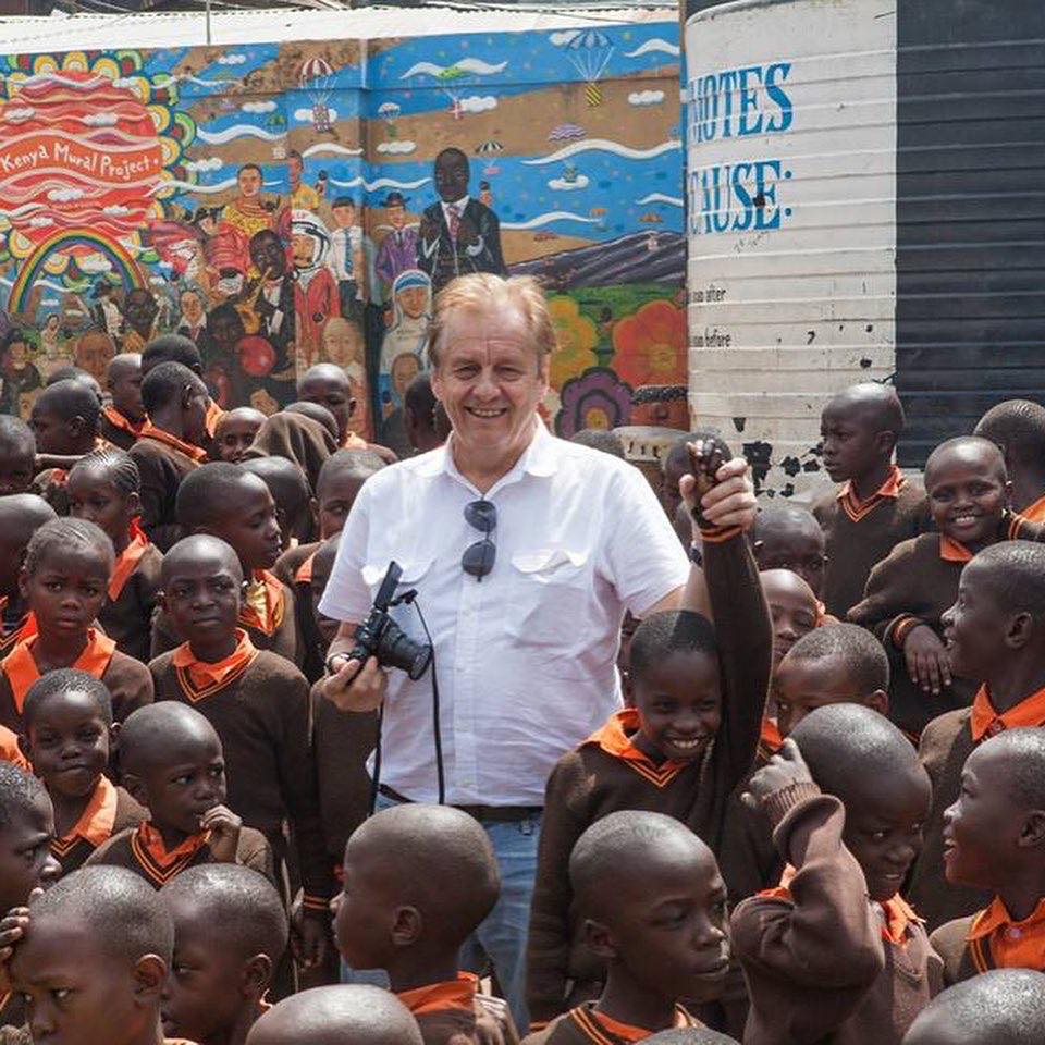 A picture of Rauli Virtanen, a Finnish traveller who is known for being the first man to travel to every country in the world, surrounded by children in Kenya.
