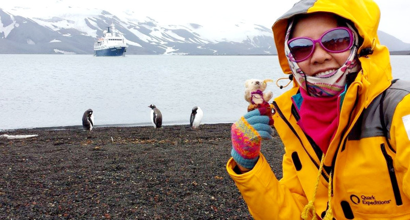 Ernestine Chan in Antarctica, posing in front of a glacier and pinguins