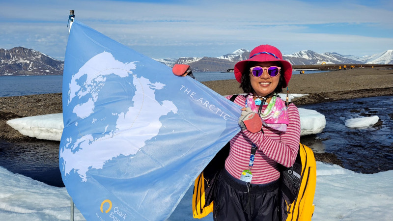 Ernestine Chan. first Canadian and first Hong Kongese woman to visit every country in the world, during her polar expedition to the Arctic, holding a blue flag of her expedition