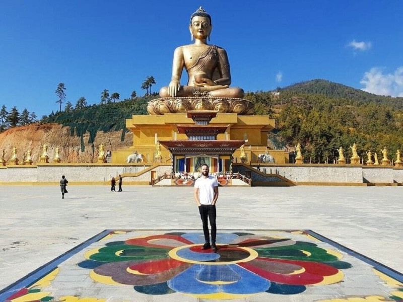 Mike Richards, author of 'The Travelling Ape,' standing proudly in front of the Great Buddha Dordenma, a colossal Shakyamuni Buddha statue in Thimphu, Bhutan, commemorating the 60th anniversary of the fourth king, Jigme Singye Wangchuck.
