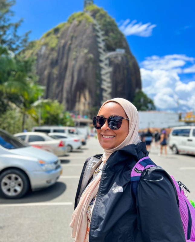 Bahraini photographer Rasha Yousif posing with her sunglasses anc backpack in front of the mountain