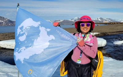 Ernestine Chan. first Canadian and first Hong Kongese woman to visit every country in the world, during her polar expedition to the Arctic, holding a blue flag of her expedition