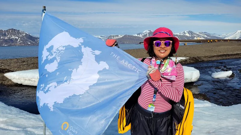 Ernestine Chan. first Canadian and first Hong Kongese woman to visit every country in the world, during her polar expedition to the Arctic, holding a blue flag of her expedition