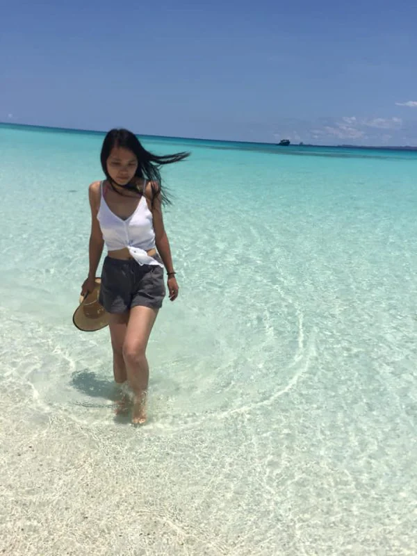 Sabrina, Chinese female solo traveller visiting Madagascar, posing in the blue waters of the Indian Ocean.